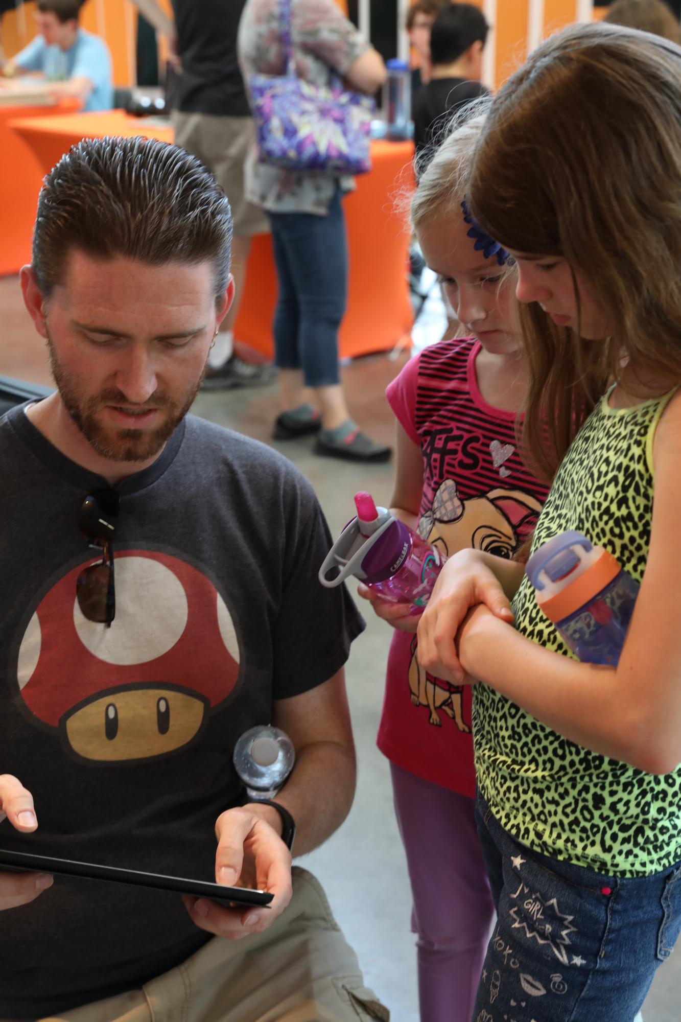 Matt Loachman, an RIT alumni, plays the video game, Crazy Platez, with his daughters Jaci (9) and Ada (6) at the Rochester Game Festival at the Gene Polisseni Center in Henrietta, N.Y. on Sept. 15, 2018. Photo by Cheyenne Boone
