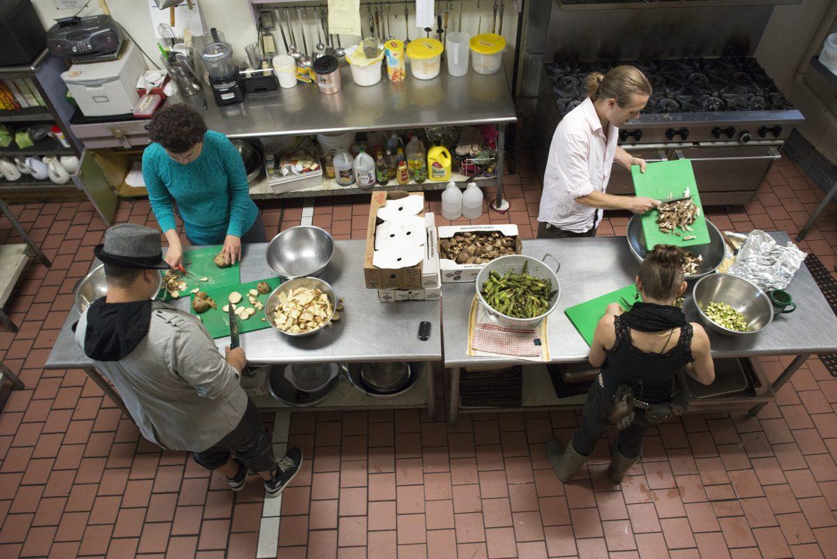 Food Not Bombs volunteers cut donated food to prepare for community dinner on Jun. 27, 2015 in Rochester, N.Y. Photography by Kristen McNicholas.