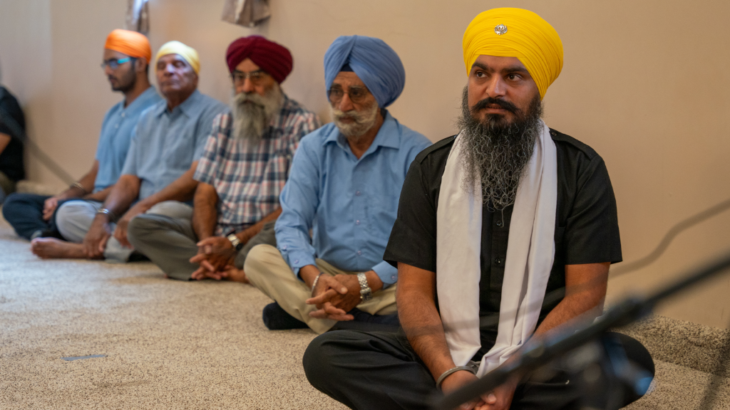 Sikh Society volunteer Ajay Singh (right) sits in the prayer room during Sunday service. Photography by Travis LaCoss