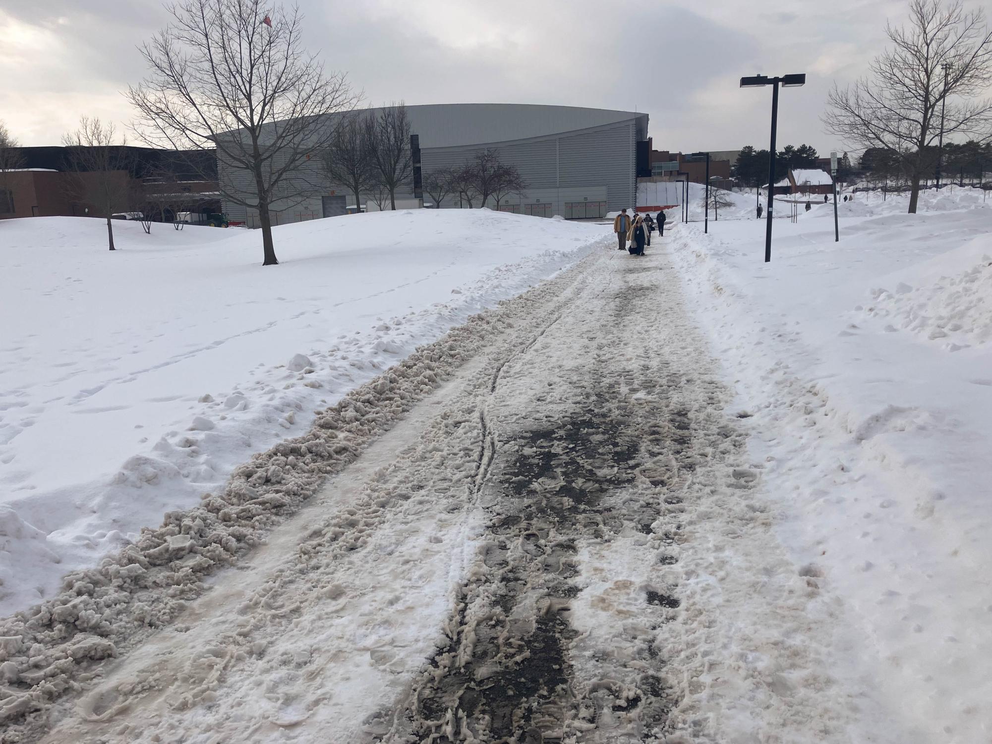 Students walk down a snow and slush-covered sidewalk at RIT outside the Gordon Field House on Feb. 10, 2026.