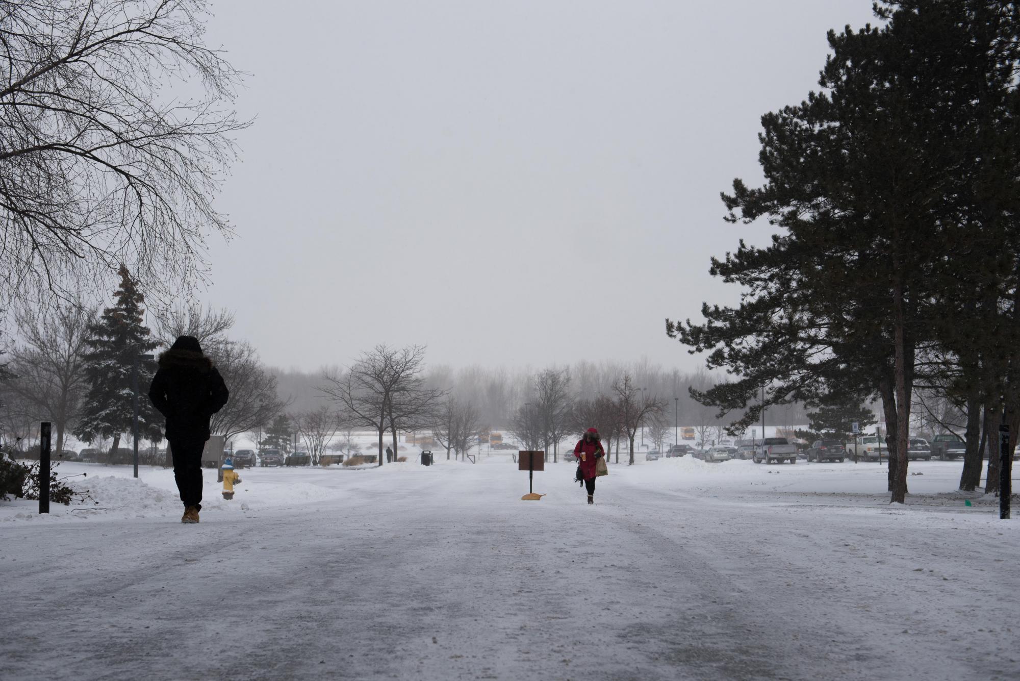 Pedestrians walk up the sidewalk on the north side of RIT's campus in front of Booth and Gannett halls on Feb. 13, 2016. Photograph by Kristen McNicholas.